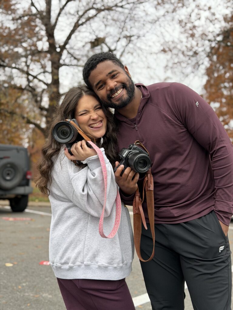 Sean & Kat Photography owners. A married coupled holding cameras on a Autumn afternoon.
